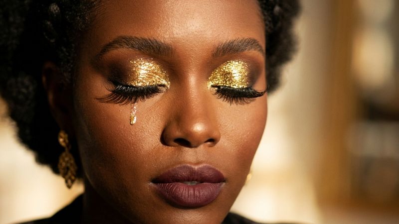 ultry gold glitter eye makeup Black woman mahogany skin eyes closed dramatic lashes golden light editorial luxury