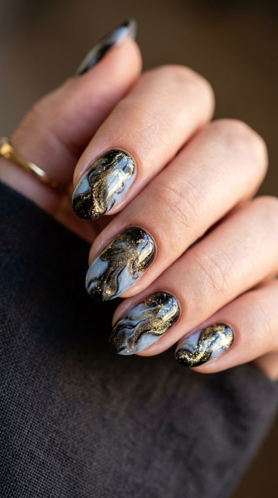 Trendy gel-ink effect nails with gold shimmer creating artistic inkblot pattern