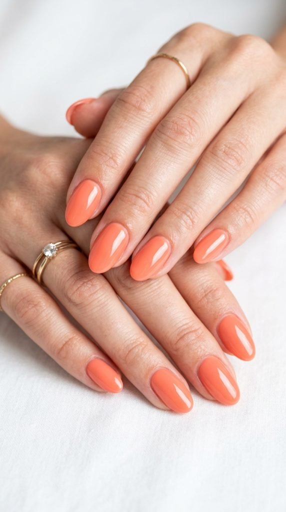 Warm coral dip nails showing vibrant peach-coral tone and polished finish